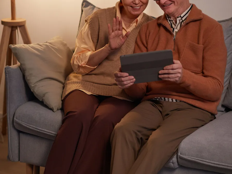 Couple de seniors regardant des photos en famille sur une tablette, lumière chaleureuse